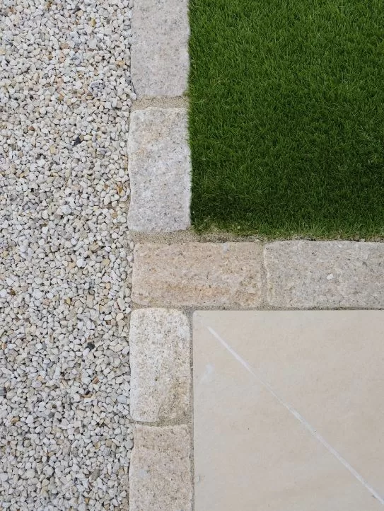 Cobble brick edging on porcelain patio and artificial grass